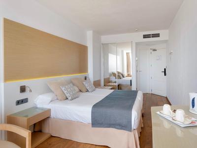 Modern eingerichtetes Hotelzimmer mit Doppelbett, Nachttischen und einem Schreibtisch mit Wasserkocher.