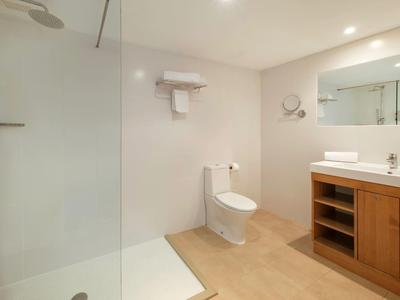 Modernes Badezimmer mit Dusche, Toilette und Holzmöbel mit Waschbecken und Spiegel.