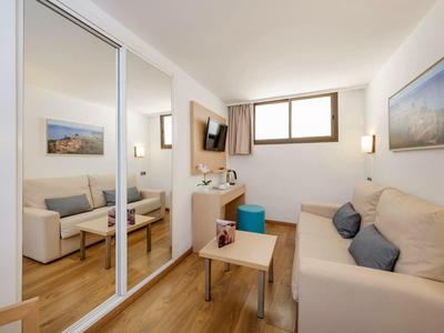 Hell eingerichtetes Wohnzimmer mit hellen Sofas, Holzboden und großen Spiegel-Schranktüren.