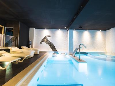 Espace bien-être moderne avec piscine, jacuzzi intégré et transats confortables.