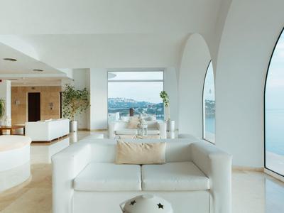 Chambre d'hôtel moderne avec mobilier blanc et grande fenêtre donnant sur la mer.