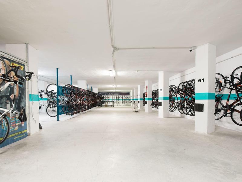 Grand local à vélos avec de nombreux vélos suspendus aux murs et debout à l'intérieur.