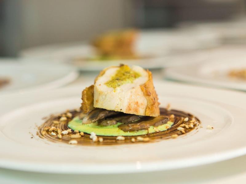 Plat gastronomique joliment dressé avec du pain, de la sauce et des graines sur une assiette blanche.