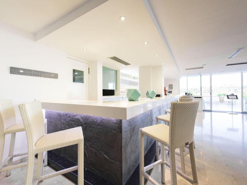 Bar d'hôtel moderne avec des chaises blanches et un espace lumineux et ouvert avec lumière naturelle.