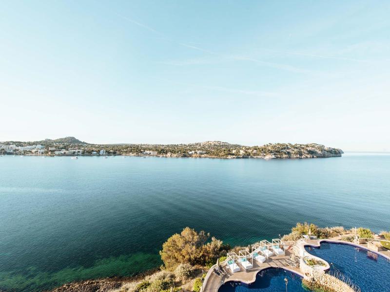 Vue sur une côte calme avec de l'eau claire et une piscine au premier plan.