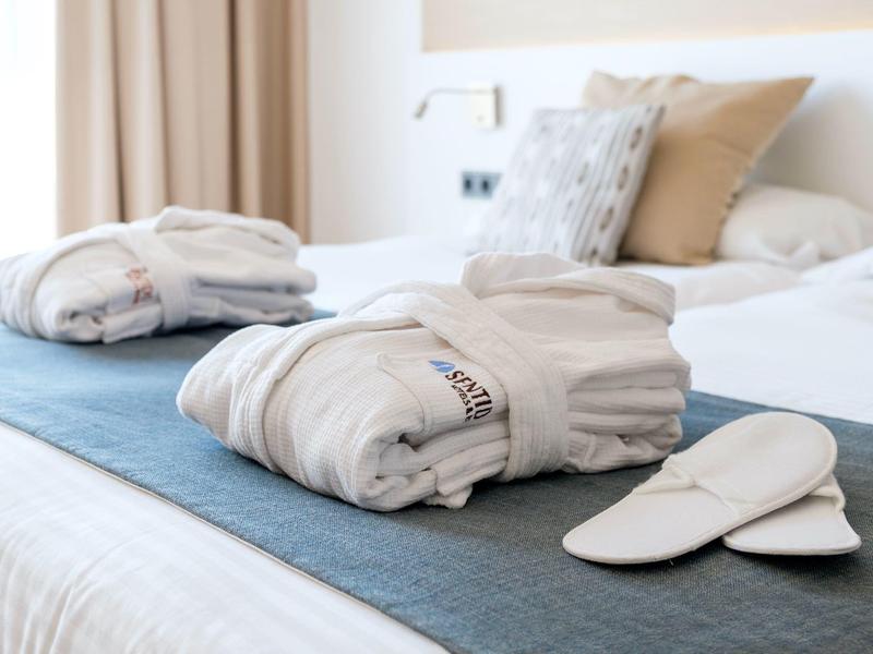 Gepacktes Bademantel-Set und Hausschuhe auf dem Bett in einem Hotelzimmer.