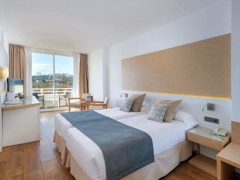 Modernes Hotelzimmer mit Doppelbett, Schreibtisch und Balkon mit Ausblick.