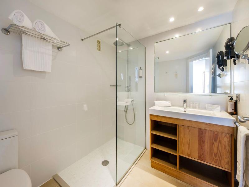 Modernes Badezimmer mit begehbarer Dusche, großem Spiegel und Holzwaschtisch.