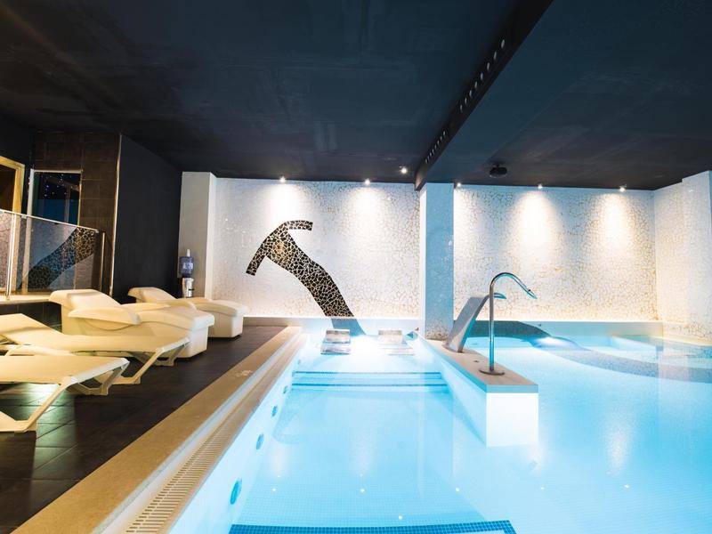 Espace bien-être moderne avec piscine, jacuzzi intégré et transats confortables.