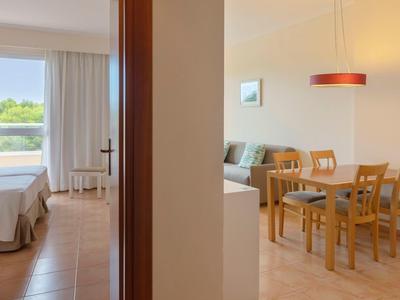 Vista attraverso un corridoio su una camera da letto con finestra e una sala da pranzo con tavolo e sedie.