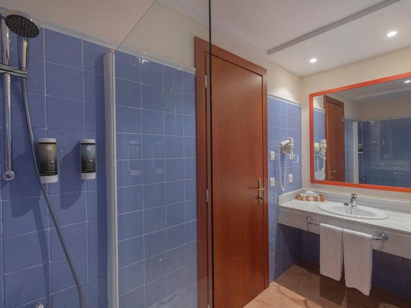 Bagno moderno con piastrelle blu, grande specchio e lavabo con asciugamani.