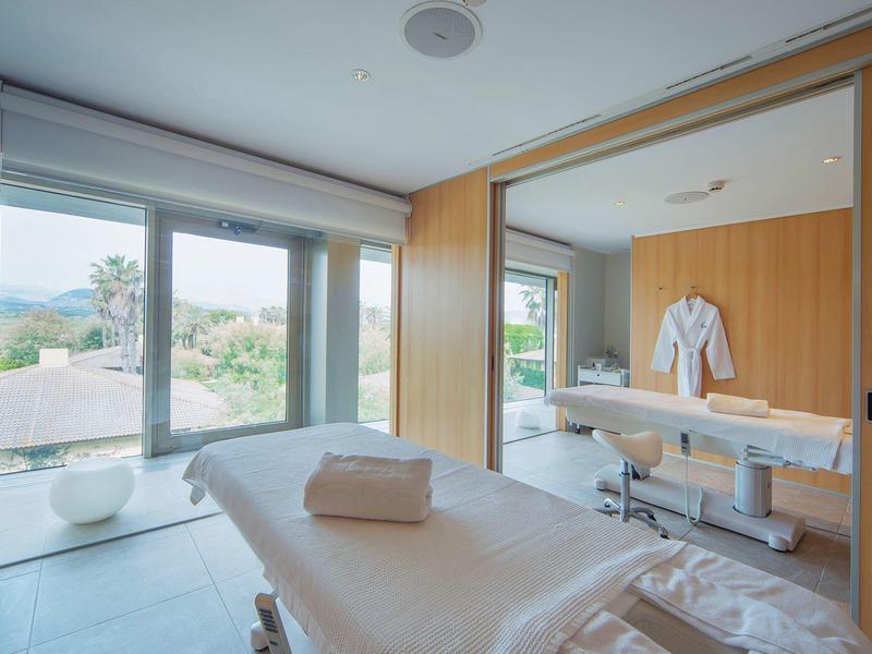 Salle de bien-être moderne avec table de massage et grande fenêtre avec vue.