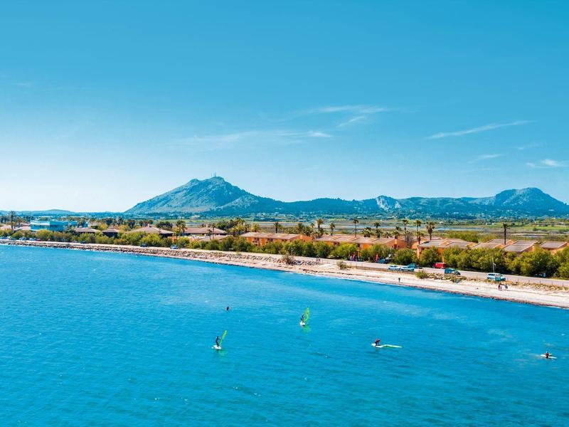 Vue côtière sur une mer bleue avec plage et montagnes à l'arrière-plan.