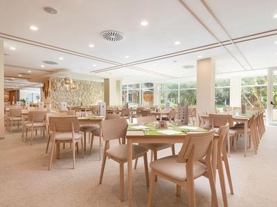 Jasna, nowoczesna restauracja z wygodnymi krzesłami i stołami, dużymi oknami i naturalnym światłem.