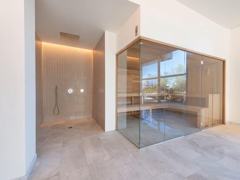 Area benessere moderna con bagno turco e doccia in design luminoso e minimalista.