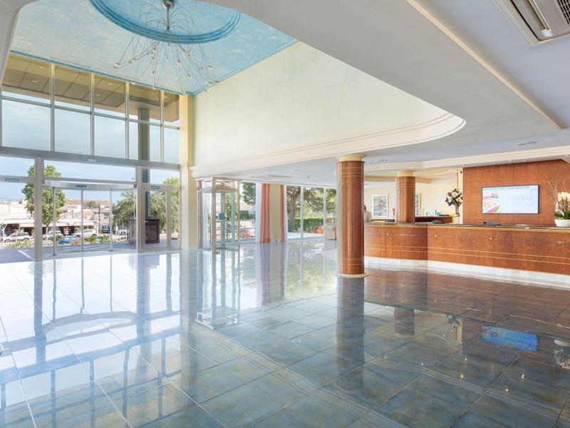 Luminosa hall d'hotel con colonne moderne, reception e grandi finestre di vetro