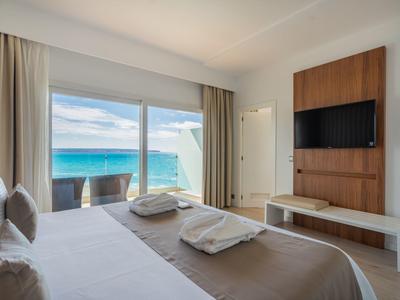 Elegantní hotelový pokoj s balkonem a výhledem na moře, televizí na stěně.