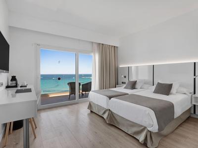 Moderní hotelový pokoj se dvěma jednolůžky a výhledem na moře z balkonu.