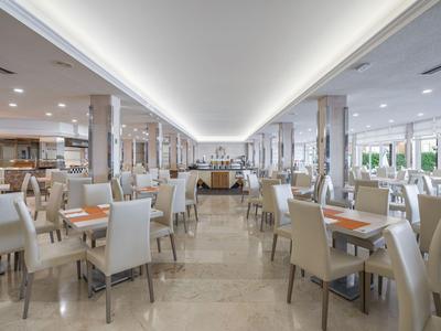 Großer eleganter Speisesaal in einem Hotel mit hellen Stühlen und Tischen.