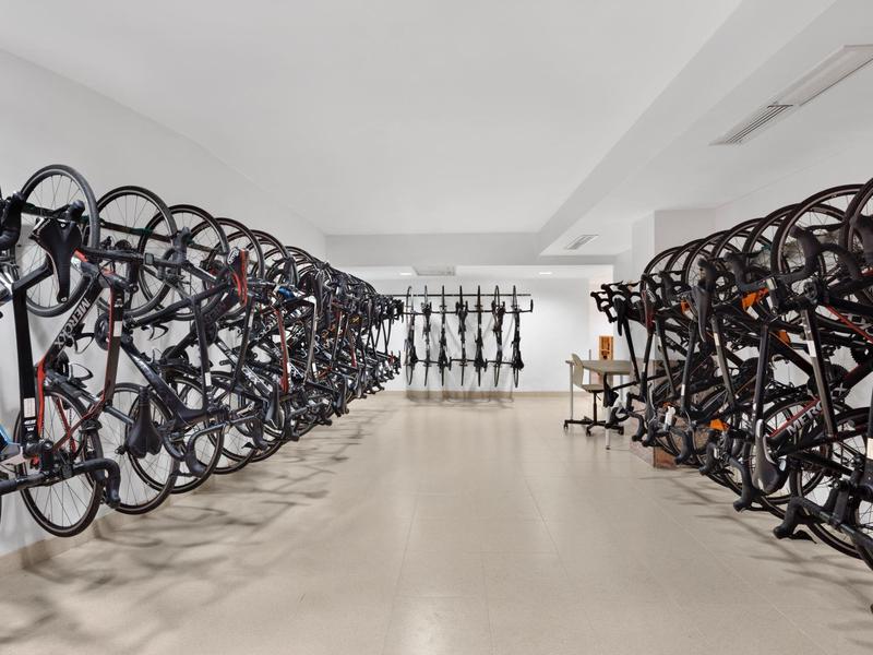 Moderní a dobře uspořádaná kolárna s několika řadami kol uvnitř.