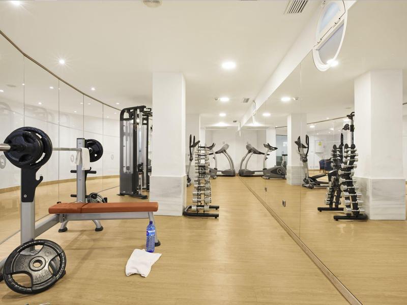 Moderní posilovna s vybavením a velkým zrcadlem na zdi.