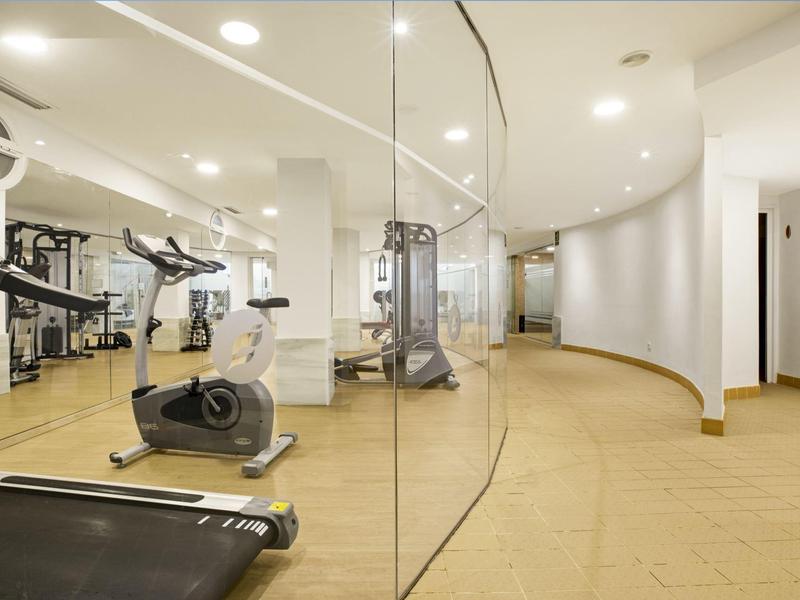 Moderní posilovna s rotopedy a běžeckými pásy v světlém, minimalistickém prostoru.