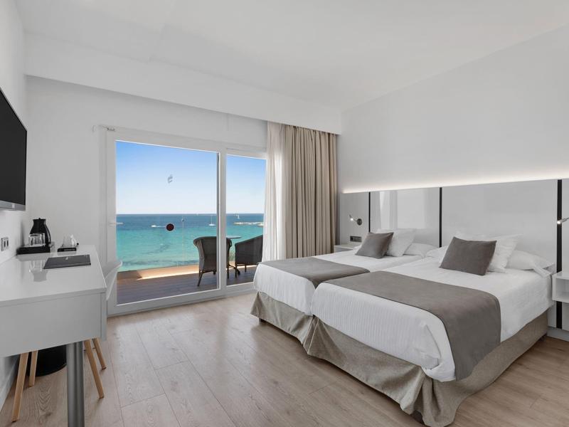 Moderní hotelový pokoj se dvěma jednolůžky a výhledem na moře z balkonu.