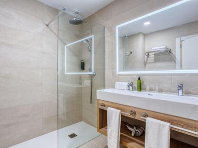 Salle de bain moderne avec douche à l'italienne, miroir éclairé et lavabo avec serviettes