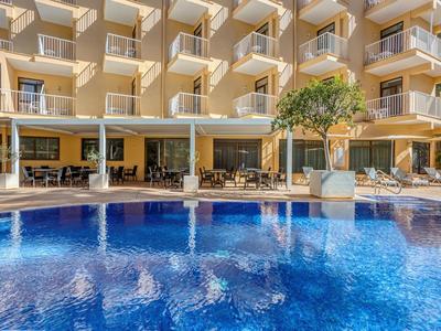 Hôtel avec piscine bleue au premier plan et façade jaune avec balcons