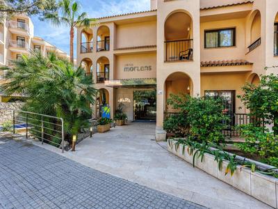 Entrée d'un hôtel à plusieurs étages avec une architecture méditerranéenne et une végétation luxuriante.