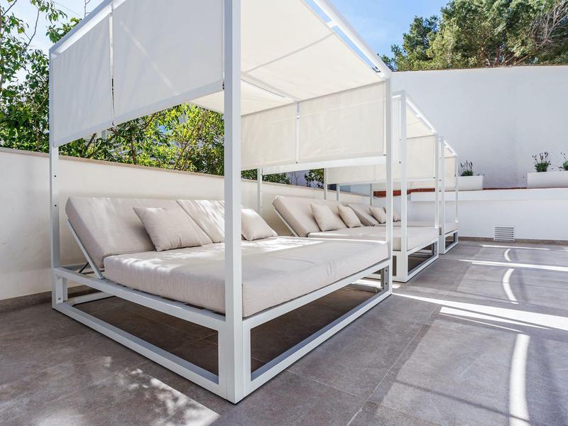 Terrasse blanche avec chaises longues rembourrées et structures d'ombre modernes.