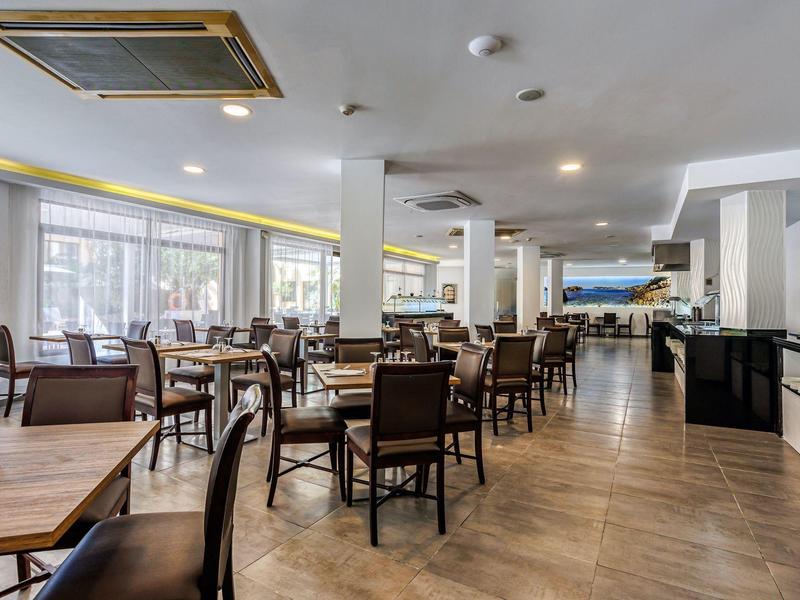 Restaurant lumineux avec sols en bois, tables en bois et chaises marron, grandes fenêtres.