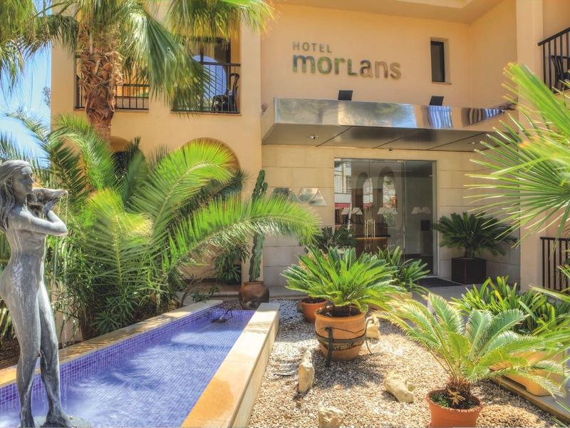 Cour intérieure d'hôtel avec fontaine, sculpture et plantes tropicales.