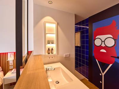Modern bathroom with wooden countertop, small recessed shelf, and colorful door artwork.