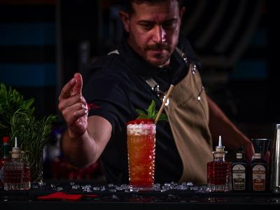 Bartender preparing a cocktail with ice behind the bar.