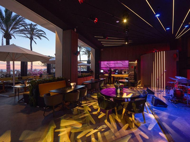 Modern restaurant with indoor and outdoor seating at sunset.