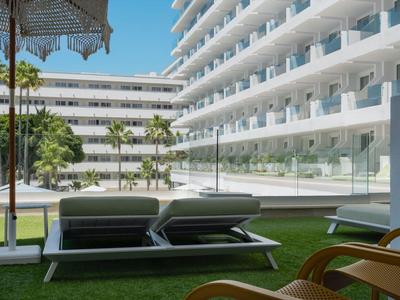 Moderner Hotelbereich mit Liegestühlen, Sonnenschirm und Blick auf weiße Balkone.
