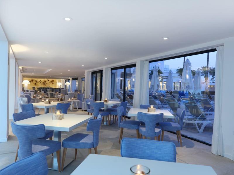 Restaurante moderno con sillas azules y grandes ventanas con vista a la terraza.