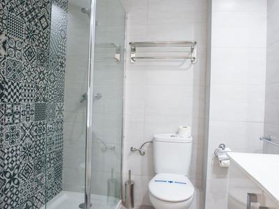 Modernes Badezimmer mit Glasdusche, Toilette und weißen Fliesen in einem Hotelzimmer.