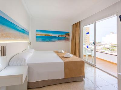 Helles Hotelzimmer mit zwei Betten, Balkon und Meeresblick, ausgestattet mit minimalistischer Dekoration.