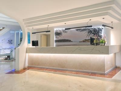 Moderner Hotel-Empfangsbereich mit beleuchtetem Tresen und minimalistischer Dekoration.