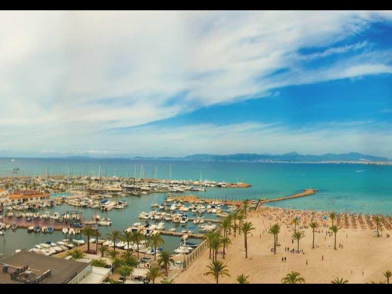 Panorama pobřežního města s přístavem, pláží a jasnou oblohou