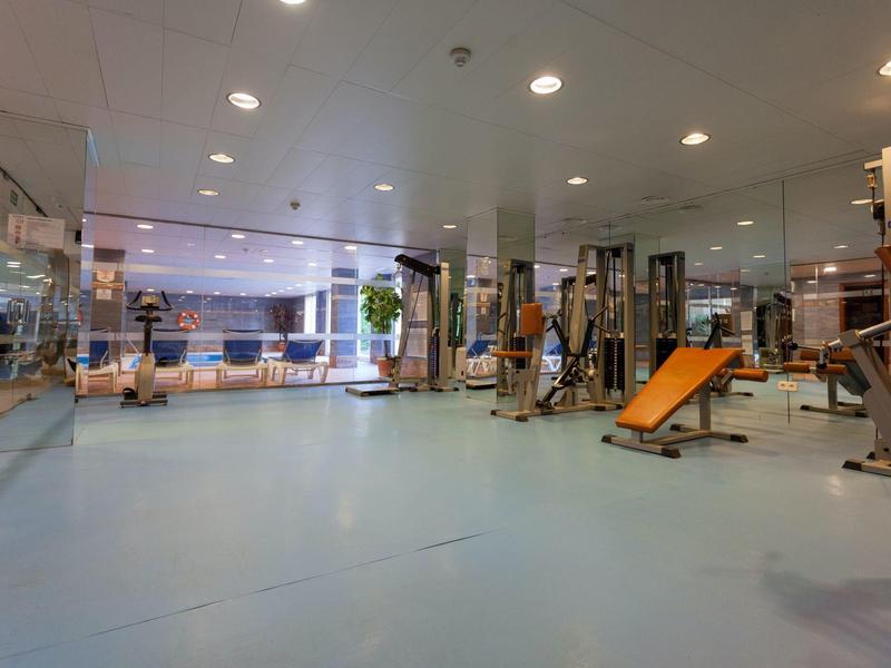 Grande salle de sport avec équipements modernes et espace lumineux et ouvert.