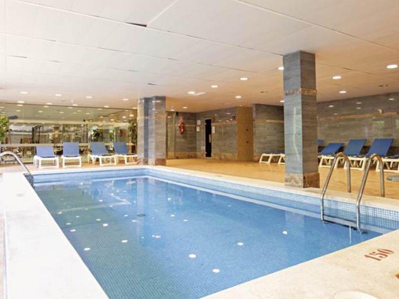 Piscine intérieure avec chaises longues bleues et murs en pierre dans un hôtel.