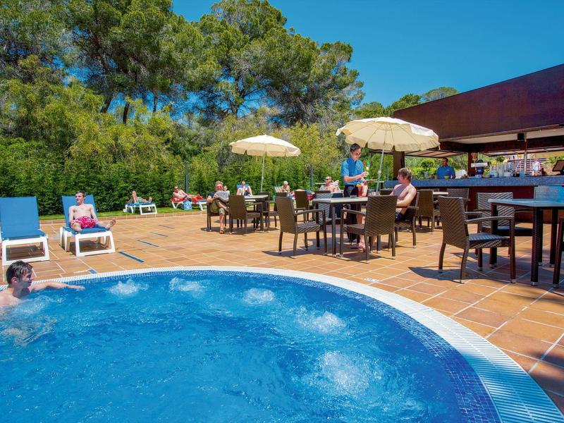 Piscine ronde avec des personnes sur des chaises longues et parasols sur la terrasse de l'hôtel