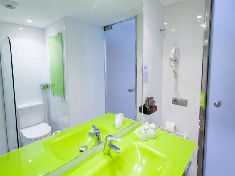 Salle de bain moderne avec lavabo vert et miroir.