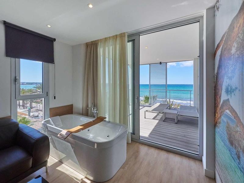 Nowoczesna łazienka hotelowa z wolnostojącą wanną i tarasem z widokiem na morze.
