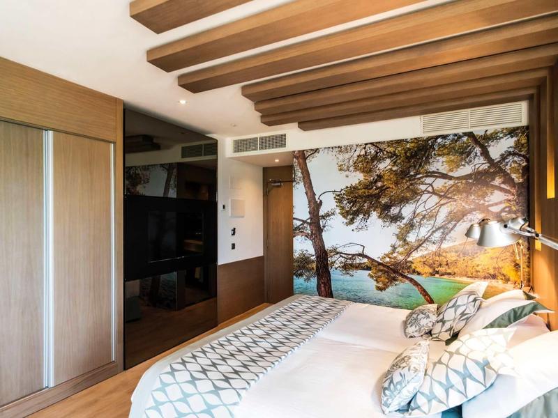 Nowoczesny pokój hotelowy z malowidłem ściennym rzeki, drewnianymi belkami i przytulnym łóżkiem.