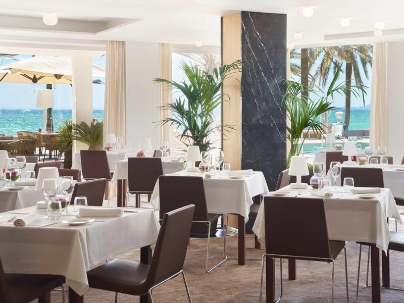 Jasna restauracja z widokiem na morze i palmy, nakryte stoły i krzesła