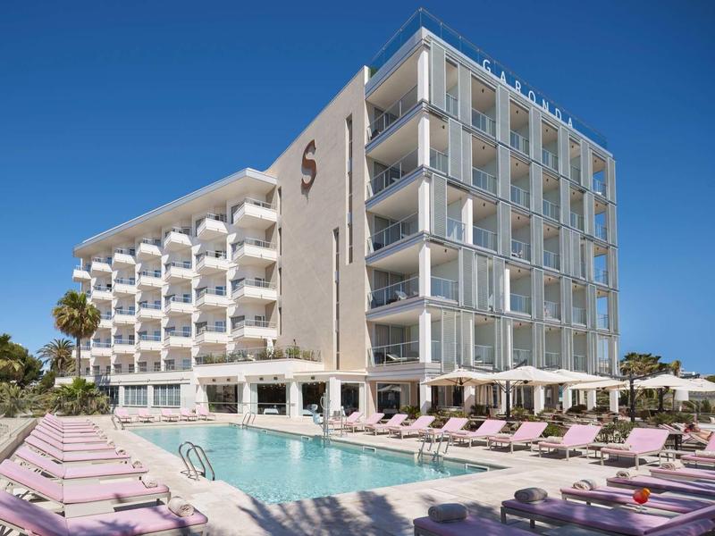 Nowoczesny hotel z basenem na świeżym powietrzu i leżakami pod jasnym niebieskim niebem